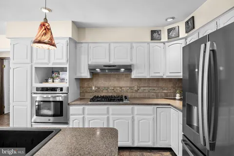 a kitchen with stainless steel appliances granite countertop a stove a sink and a refrigerator