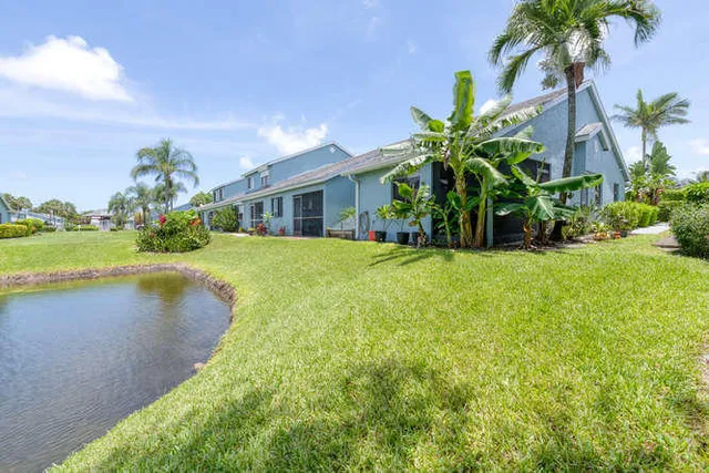 a view of a house with a yard and palm trees