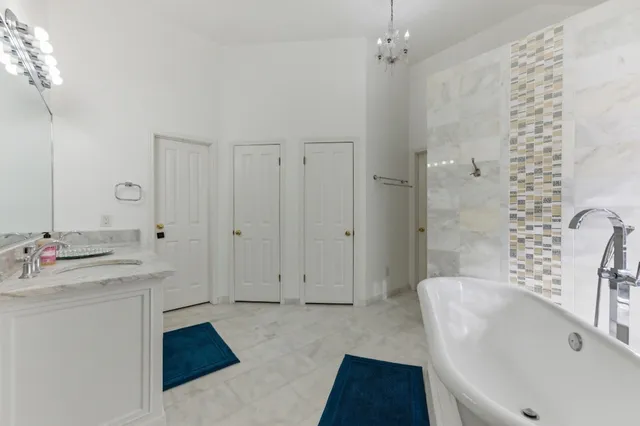 a spacious bathroom with a tub sink and mirror
