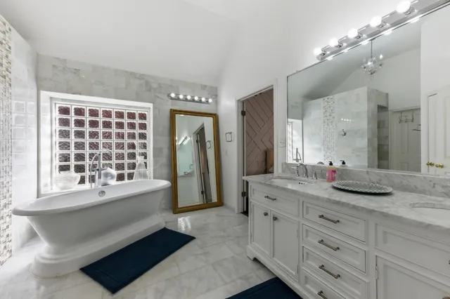a bathroom with a granite countertop sink mirror and a bathtub