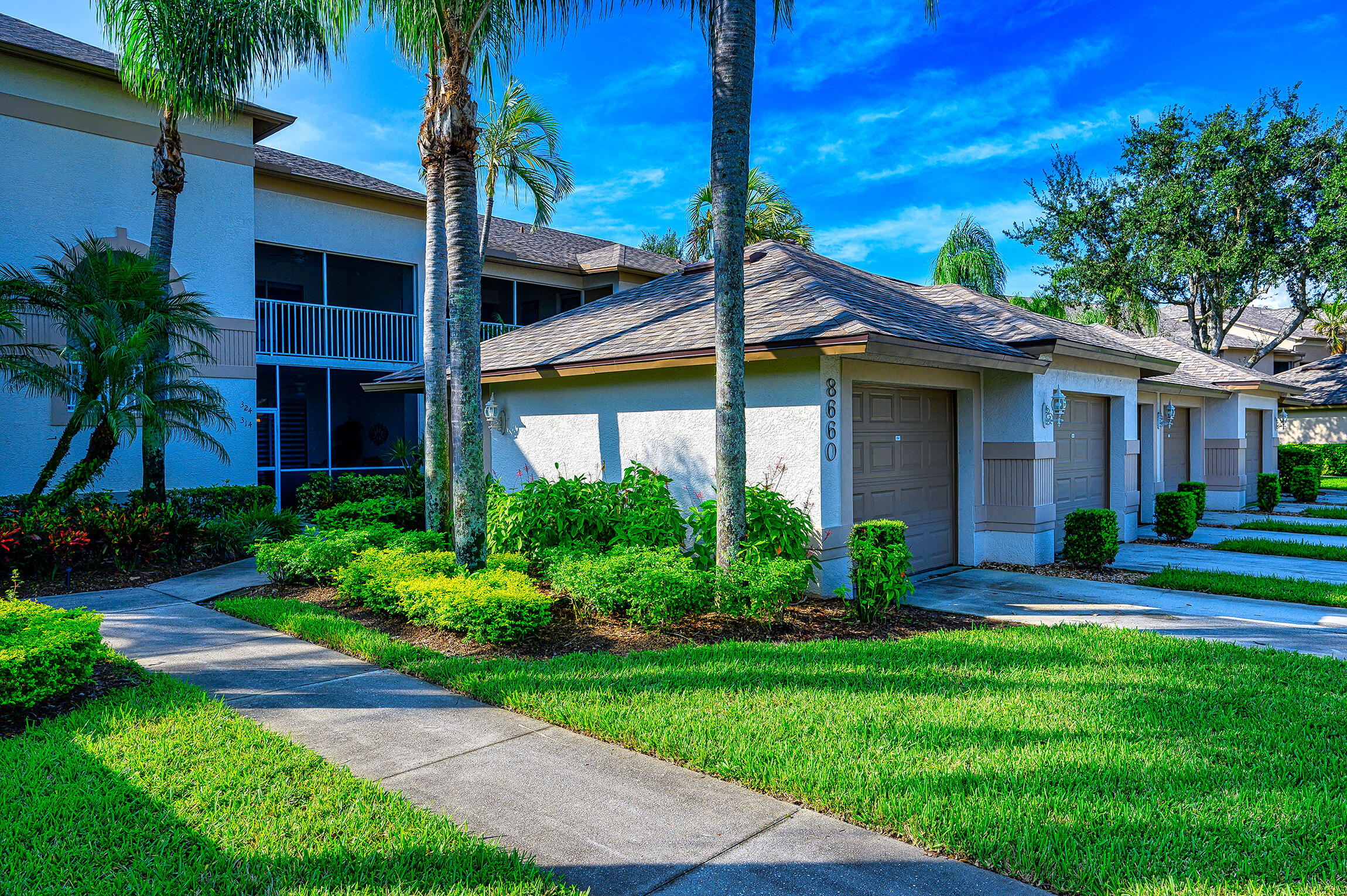 8660 Cedar Hammock Circle, Unit 314 Naples, FL 34112 - Photo 11 of 31 a front view of a house with a yard and potted plants