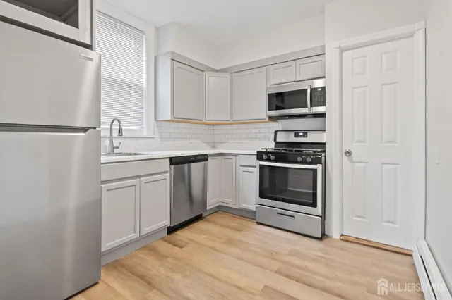 a kitchen with white cabinets and stainless steel appliances