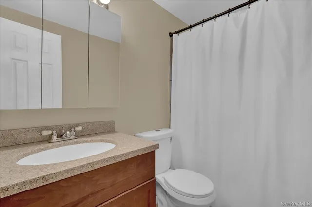 a bathroom with a granite countertop sink toilet and a mirror