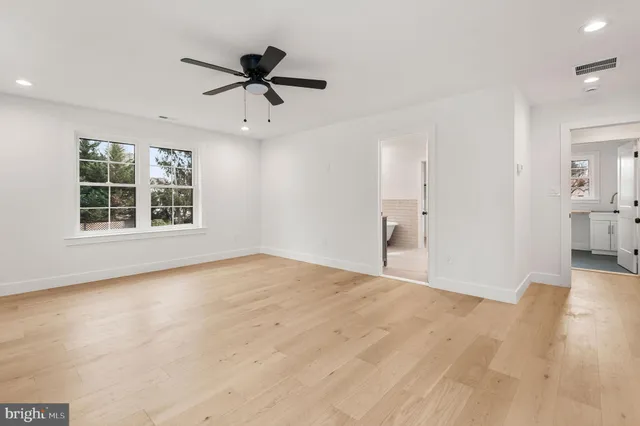 a view of an empty room with a window and a kitchen view