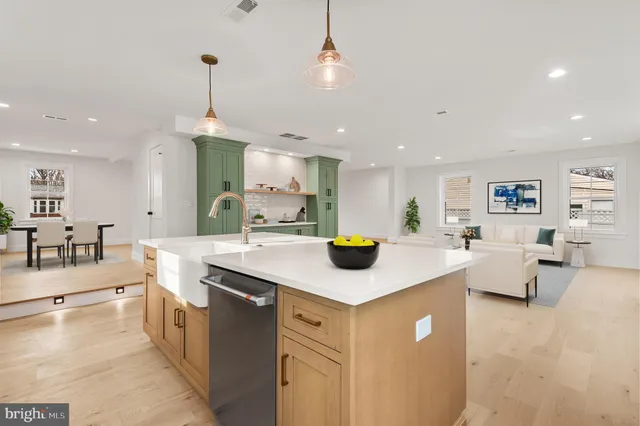 a kitchen with stainless steel appliances a sink a stove a refrigerator and white cabinets with wooden floor