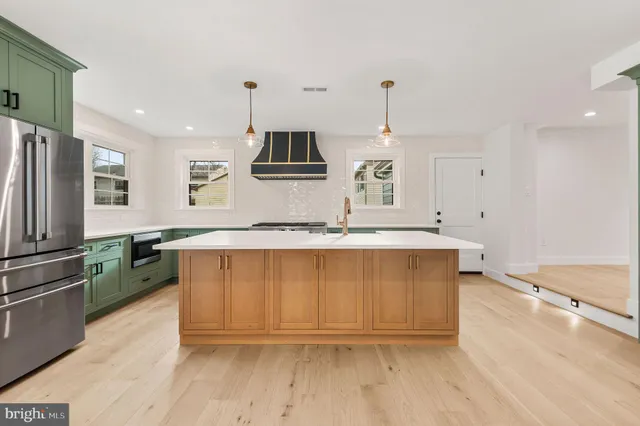 a kitchen with kitchen island granite countertop a sink cabinets and stainless steel appliances