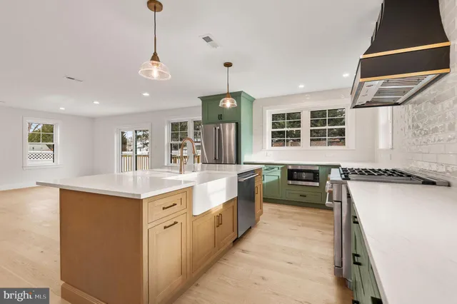 a kitchen with a stove a sink a center island and windows