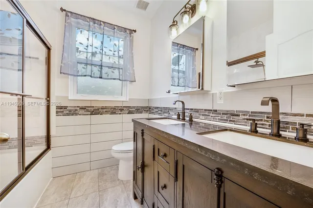 a bathroom with a granite countertop sink a toilet a mirror and shower