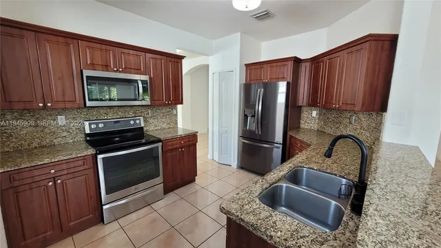 a kitchen with granite countertop a stove sink and refrigerator