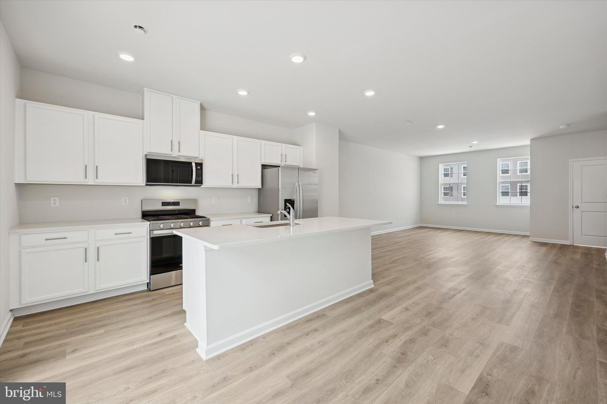 163 Sandy Rdg Road Sicklerville, NJ 08081 - Photo 9 of 30 a large white kitchen with kitchen island a sink a stove a microwave and white cabinets