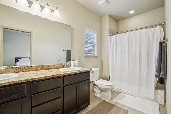 a bathroom with a granite countertop sink toilet and mirror