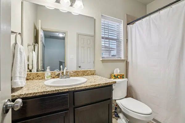 a bathroom with a granite countertop toilet sink and mirror