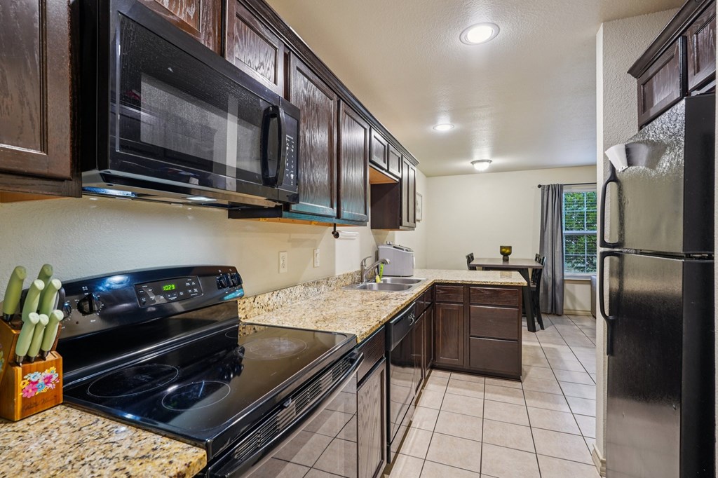2312 Sailing Way Kerrville, TX 78028 - Photo 52 of 60 a kitchen with granite countertop stainless steel appliances and wooden cabinets