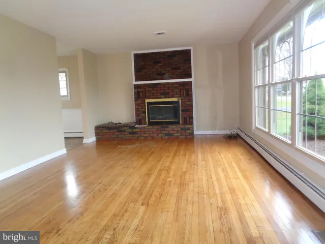 a view of empty room with wooden floor and fireplace