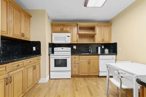 a kitchen with granite countertop white cabinets and white appliances
