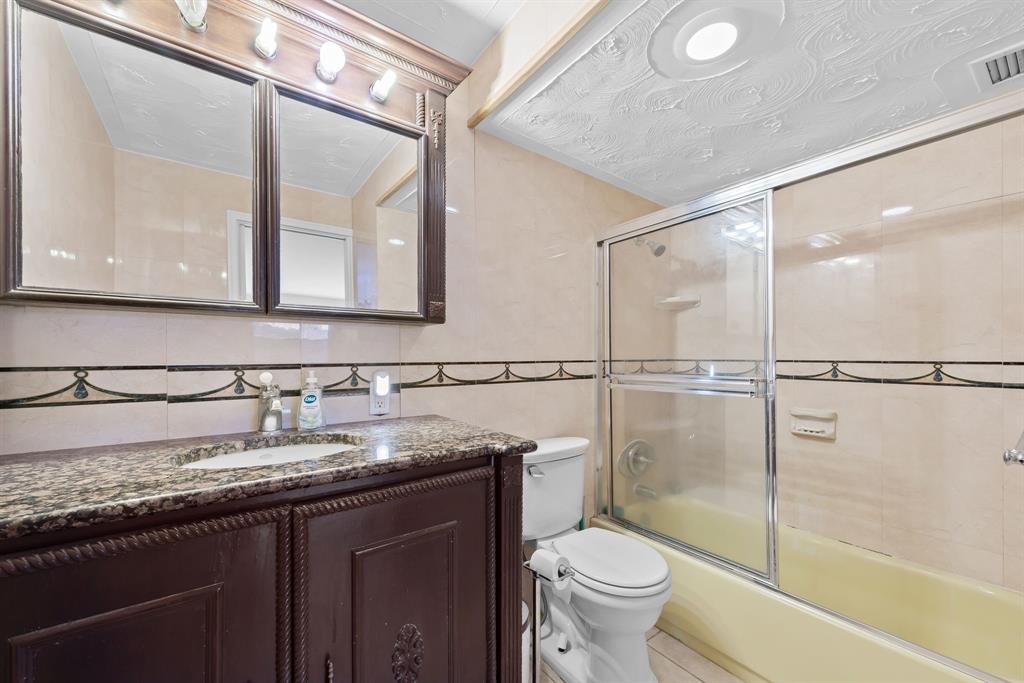 111 Golden Isles Drive, Unit B2 Hallandale Beach, FL 33009 - Photo 10 of 12 a bathroom with a granite countertop sink toilet mirror and shower
