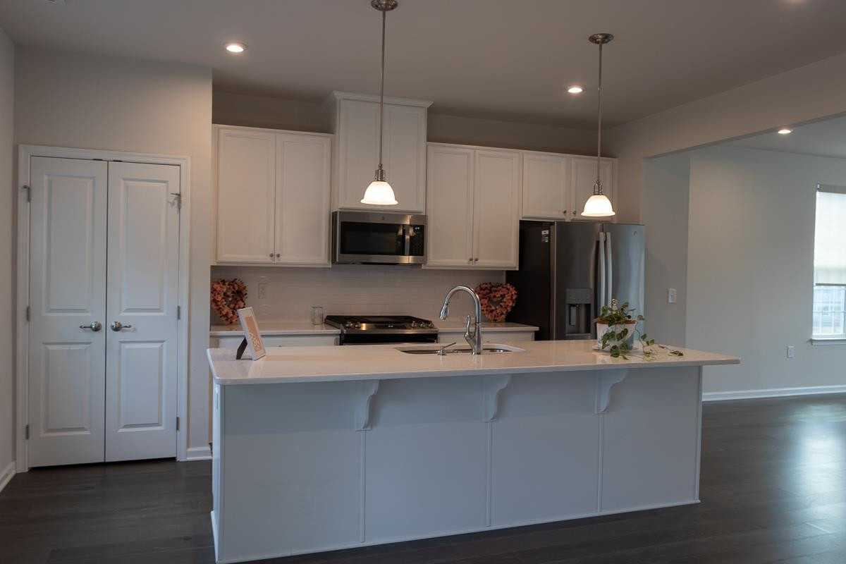 4847 Randall Road Durham, NC 27707 - Photo 5 of 25 a kitchen with stainless steel appliances a sink a stove a refrigerator and island with wooden floor