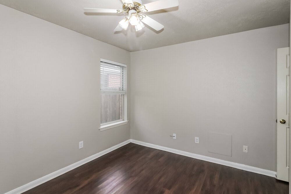 19823 Indian Cherry Forest Lane Cypress, TX 77433 - Photo 13 of 16 an empty room with wooden floor chandelier fan and windows