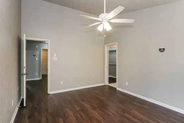 an empty room with wooden floor fan and windows