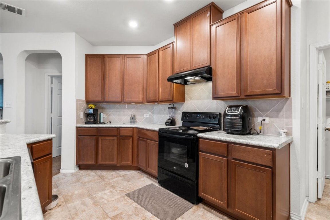 239 Crimson Lane Kyle, TX 78640 - Photo 11 of 25 a kitchen with stainless steel appliances granite countertop wooden cabinets a stove top oven a sink and dishwasher