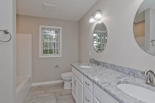 a bathroom with a granite countertop toilet a sink and a mirror