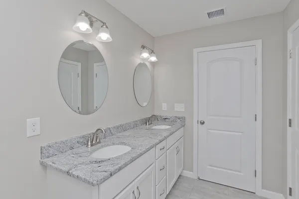 a bathroom with a granite countertop double vanity sinks and a mirror