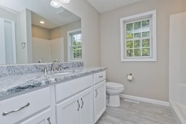 a bathroom with a granite countertop sink toilet and a mirror