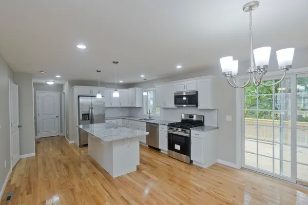 a kitchen with stainless steel appliances granite countertop a sink a stove and a wooden floors