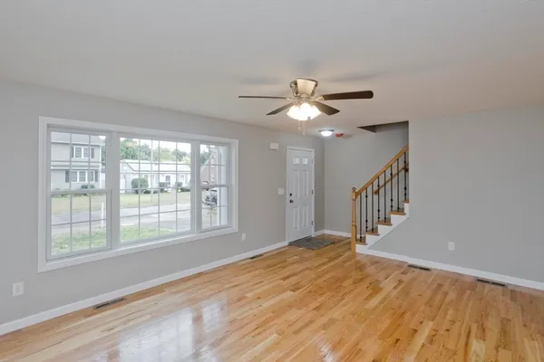 a view of an empty room with a window and wooden floor