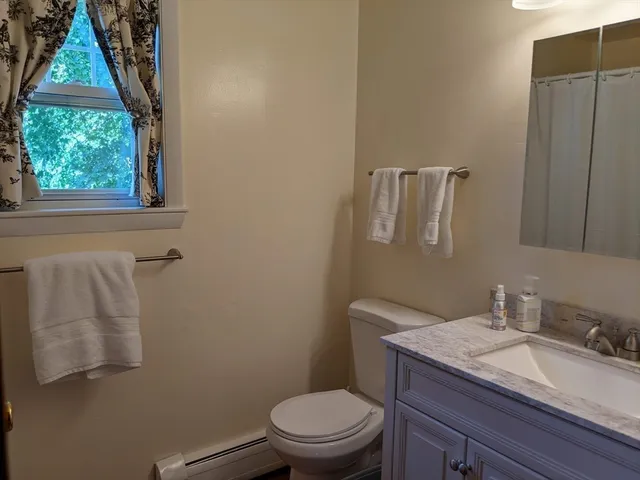 a bathroom with a granite countertop toilet a sink and a mirror