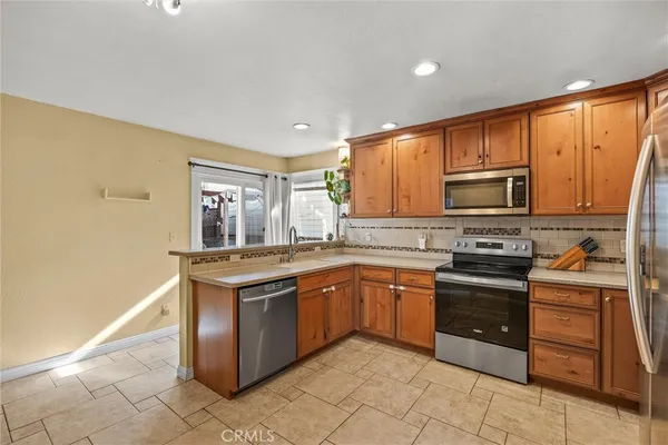a kitchen with stainless steel appliances granite countertop a stove top oven a sink dishwasher and a refrigerator