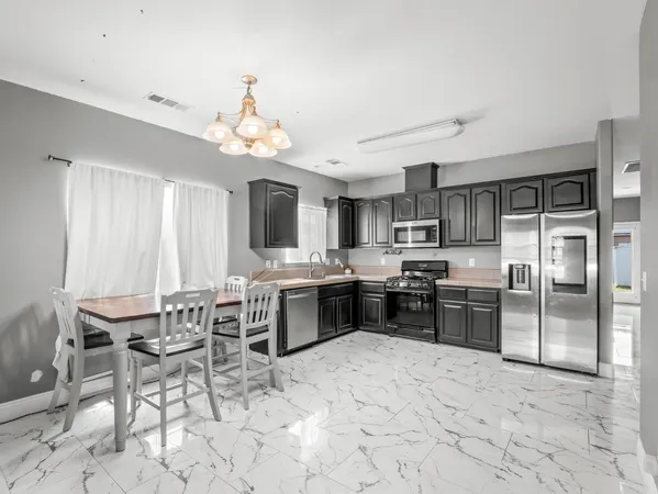 a kitchen with stainless steel appliances a refrigerator stove top oven dining table and chairs