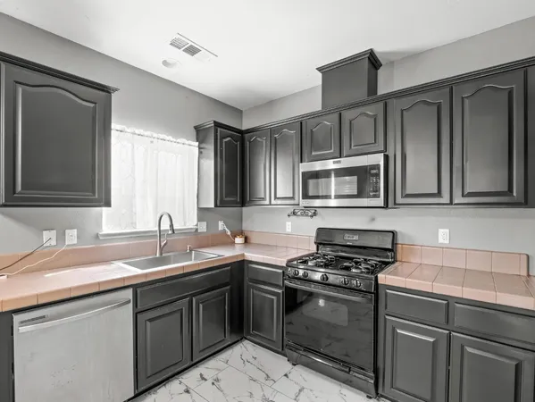 a kitchen with stainless steel appliances granite countertop a sink stove and microwave
