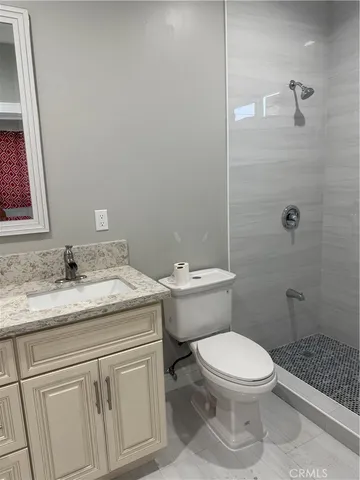 a bathroom with a granite countertop toilet a sink and a mirror