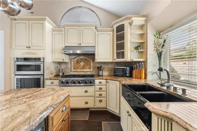 a kitchen with stainless steel appliances granite countertop a stove and a white cabinets