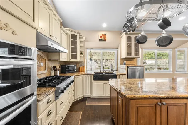 a kitchen with stainless steel appliances granite countertop a sink a stove and a wooden cabinets