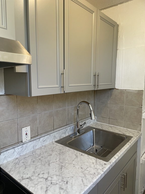 18 Lawton Avenue, Unit 3 Lynn, MA 01902 - Photo 23 of 24 a kitchen with granite countertop white cabinets and sink