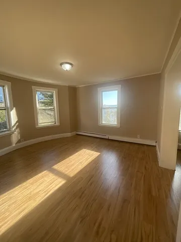 a view of empty room with window and wooden floor