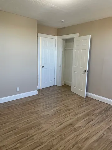 a view of an empty room with wooden floor and window