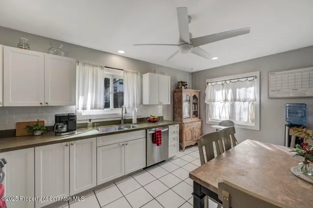 a kitchen with a stove a sink dishwasher a dining table and chairs with wooden floor