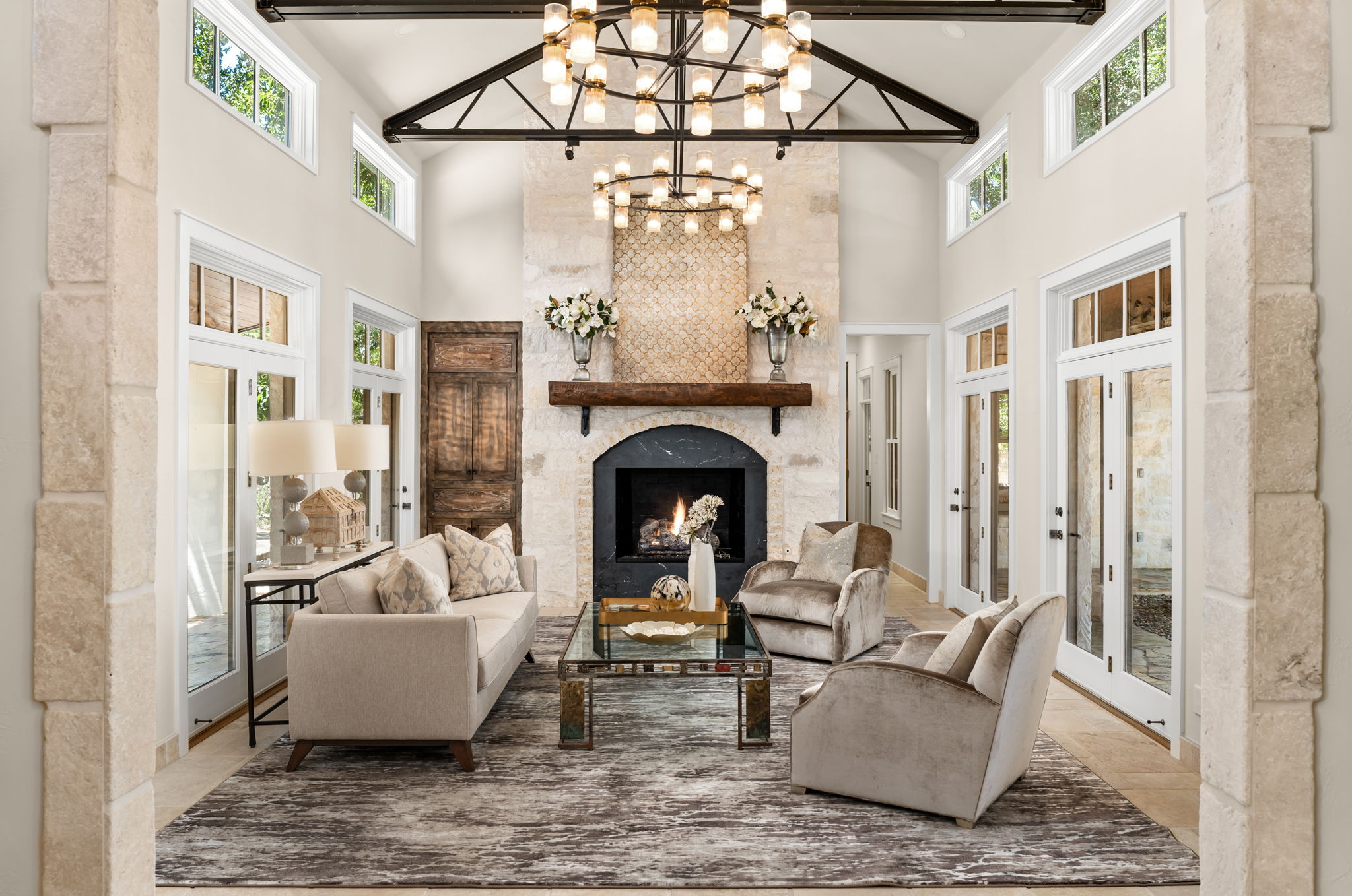 11949 Overlook Pass Austin, TX 78738 - Photo 8 of 40 Living area featuring a towering ceiling, a chandelier, healthy amount of natural light, a large fireplace, and beam ceiling