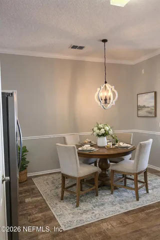 a view of a dining room and livingroom with furniture wooden floor a rug and a chandelier