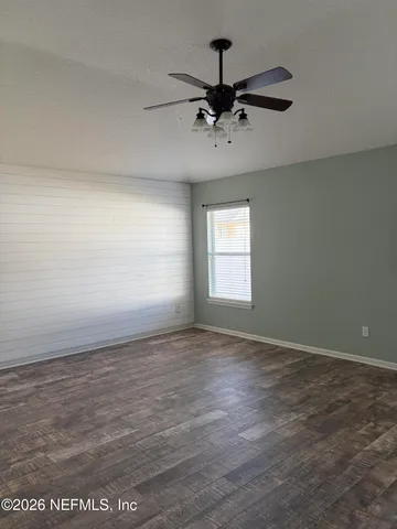 an empty room with wooden floor fan and windows