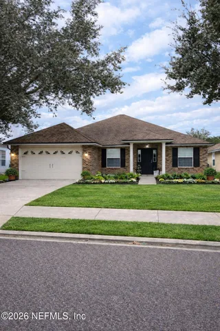 a front view of a house with a garden and trees