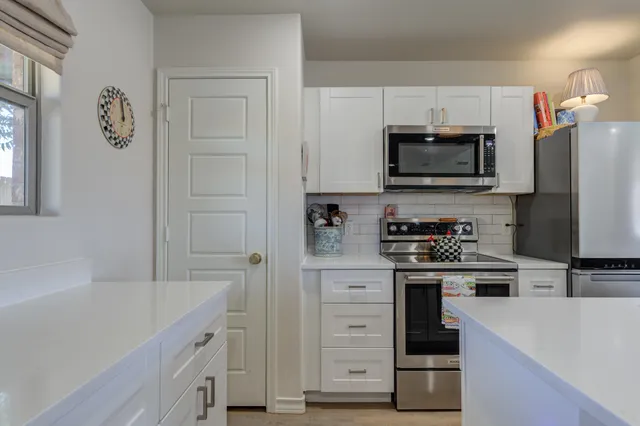 a kitchen with white cabinets and stainless steel appliances