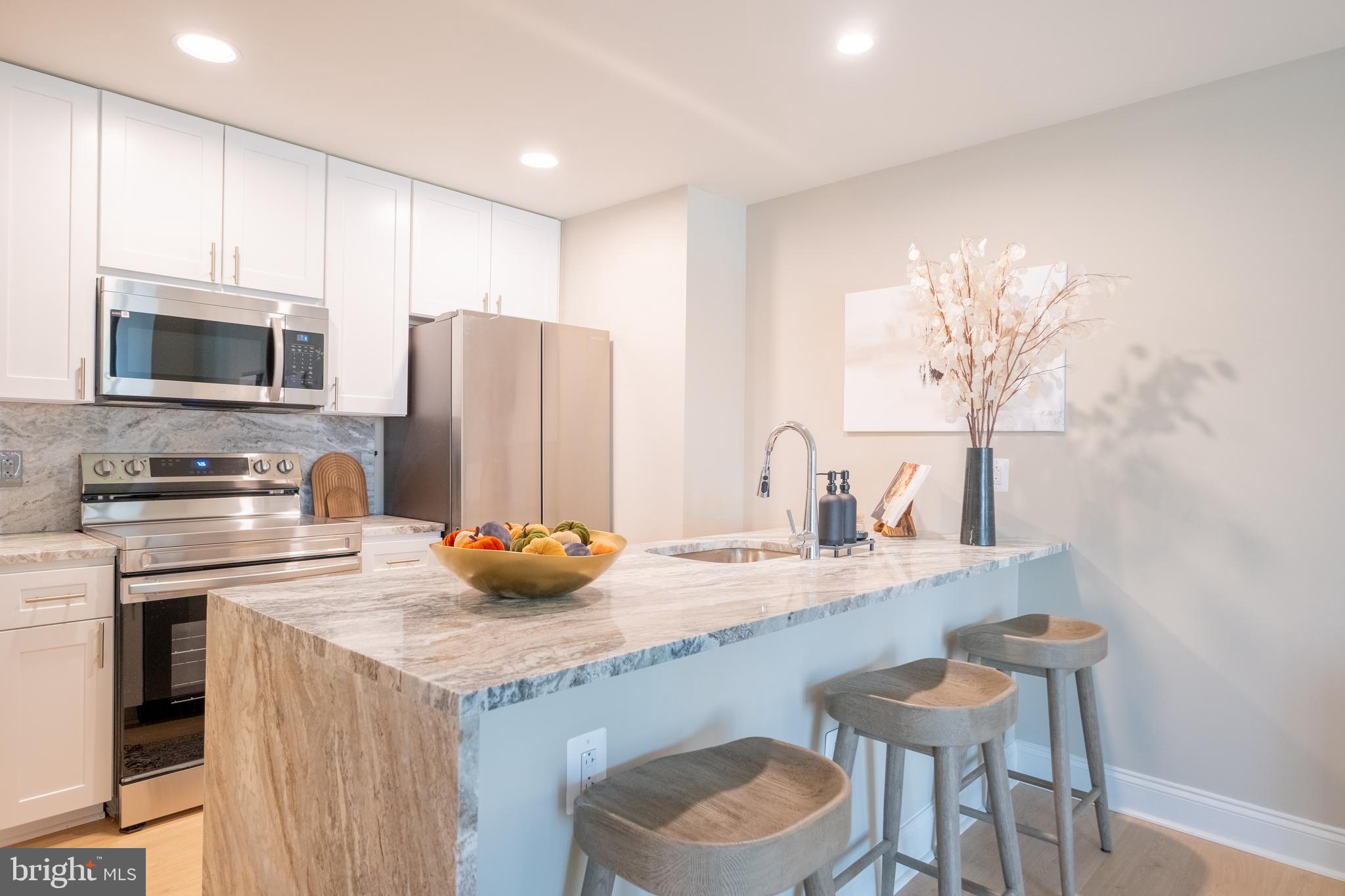 2301-61 John F Kennedy Boulevard, Unit 211 Philadelphia, PA 19103 - Photo 2 of 37 a kitchen with stainless steel appliances granite countertop a sink a stove a refrigerator cabinets and a dining table
