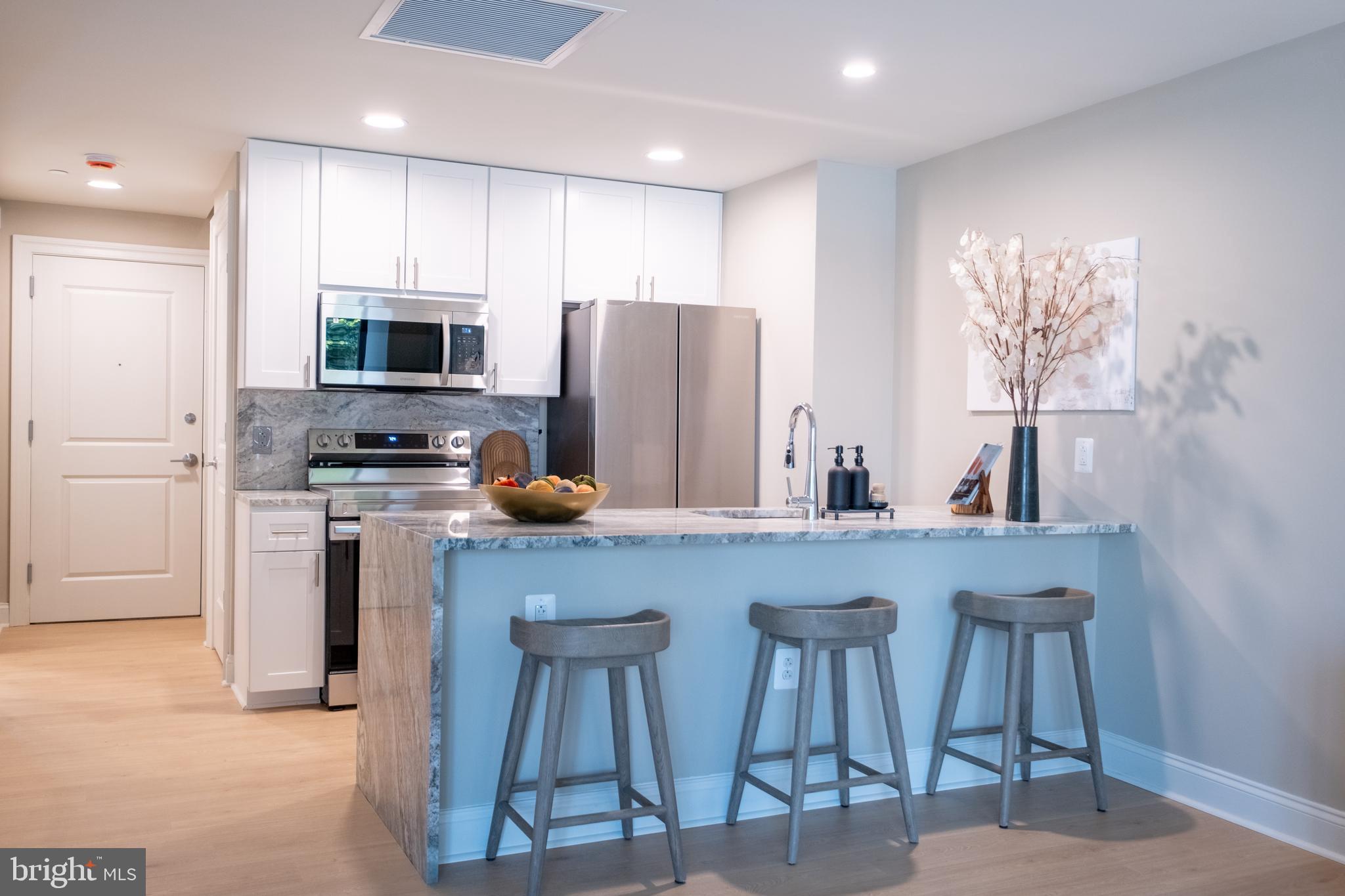 2301-61 John F Kennedy Boulevard, Unit 211 Philadelphia, PA 19103 - Photo 3 of 37 a kitchen with stainless steel appliances a refrigerator a sink a stove a dining table and chairs