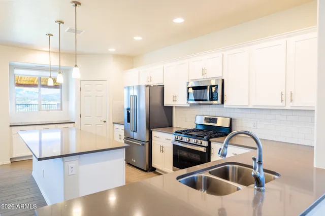 a kitchen with stainless steel appliances granite countertop a sink a stove and a refrigerator with wooden floor