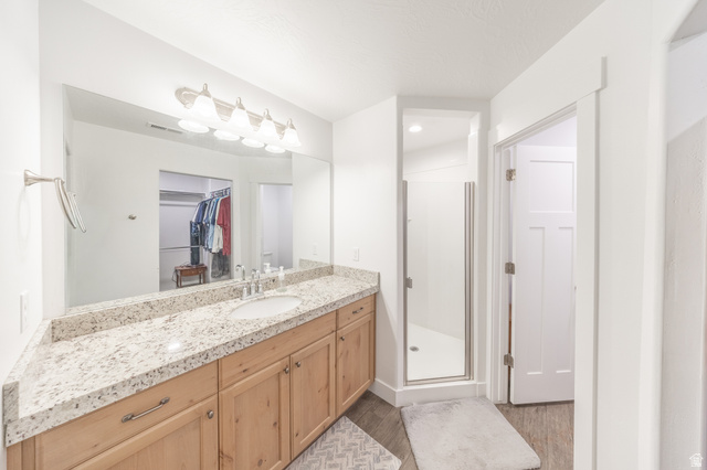 4765 Breezy Patch Road Eagle Mountain, UT 84005 - Photo 18 of 25 Bathroom featuring an extended vanity with a light-toned countertop, a single undermount sink, and wood-finish cabinetry
