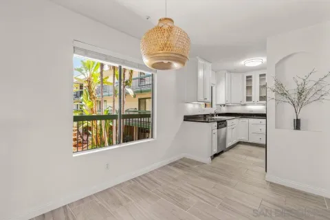 a kitchen with stainless steel appliances granite countertop a stove a sink a refrigerator and a dining table with wooden floor